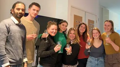Groep studenten van de OMNI hypnoseopleiding proost samen tijdens een bijeenkomst – gevoel van verbinding en een warm bad